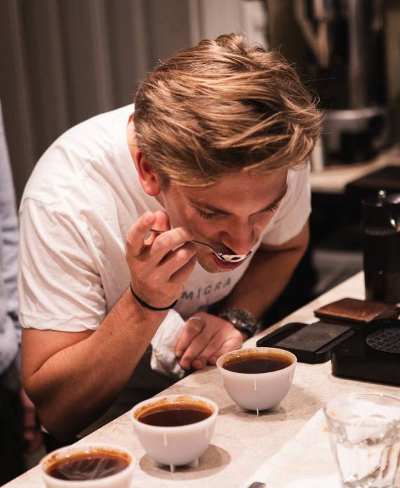 Julian Tomala konzentriert sich beim Cupping im MANANA Café über mehreren frisch aufgebrühten Kaffeeproben