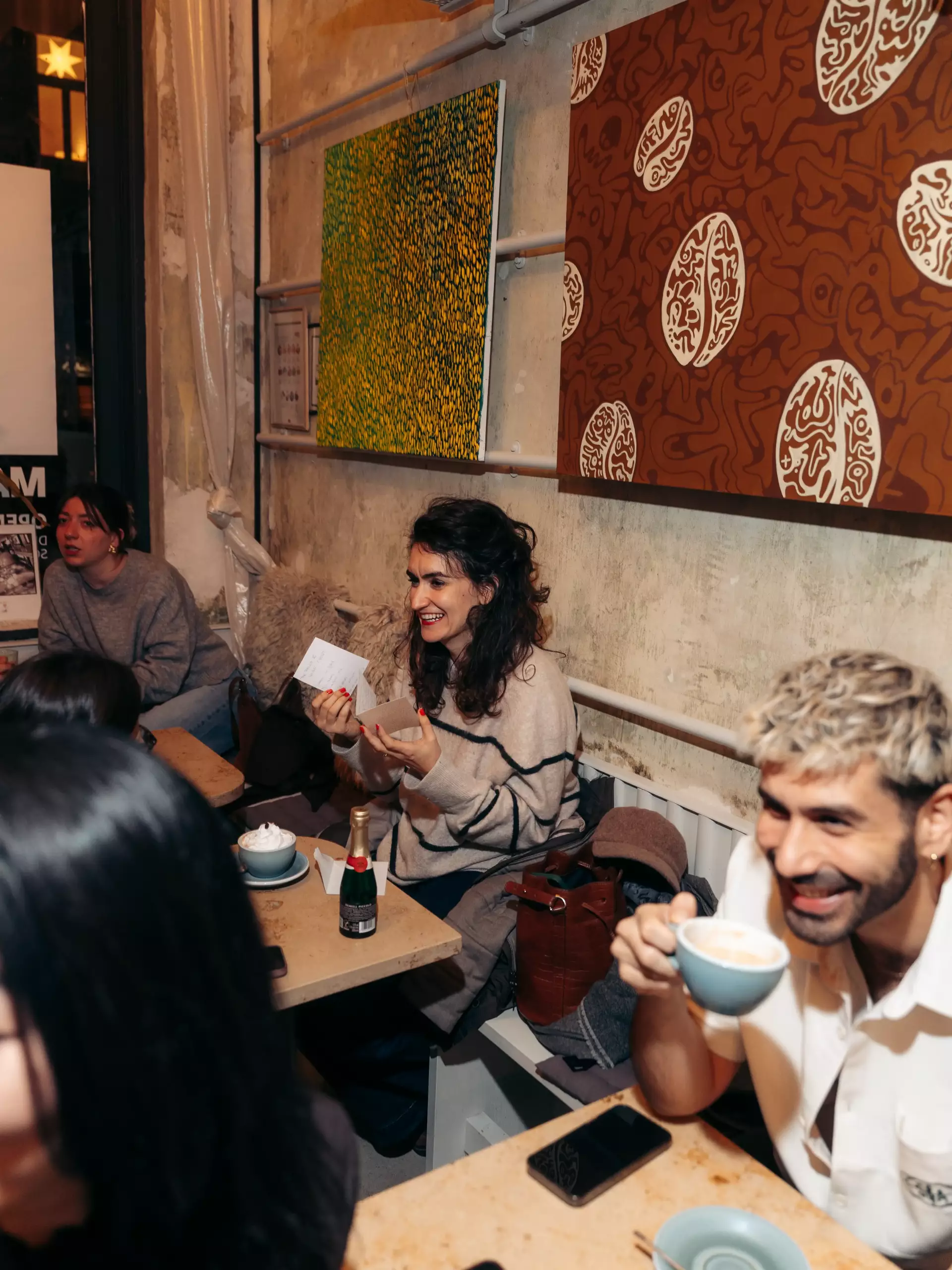 Guests sitting inside MANANA café during the GAVIE Afterwork event with gin artworks in the background.
