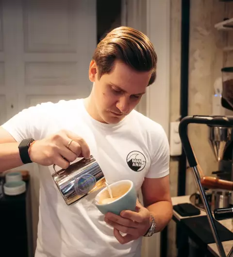 Latte Art Workshop im MANANA cafẽ – Barista gießt Milch für Latte Art in türkise Tasse