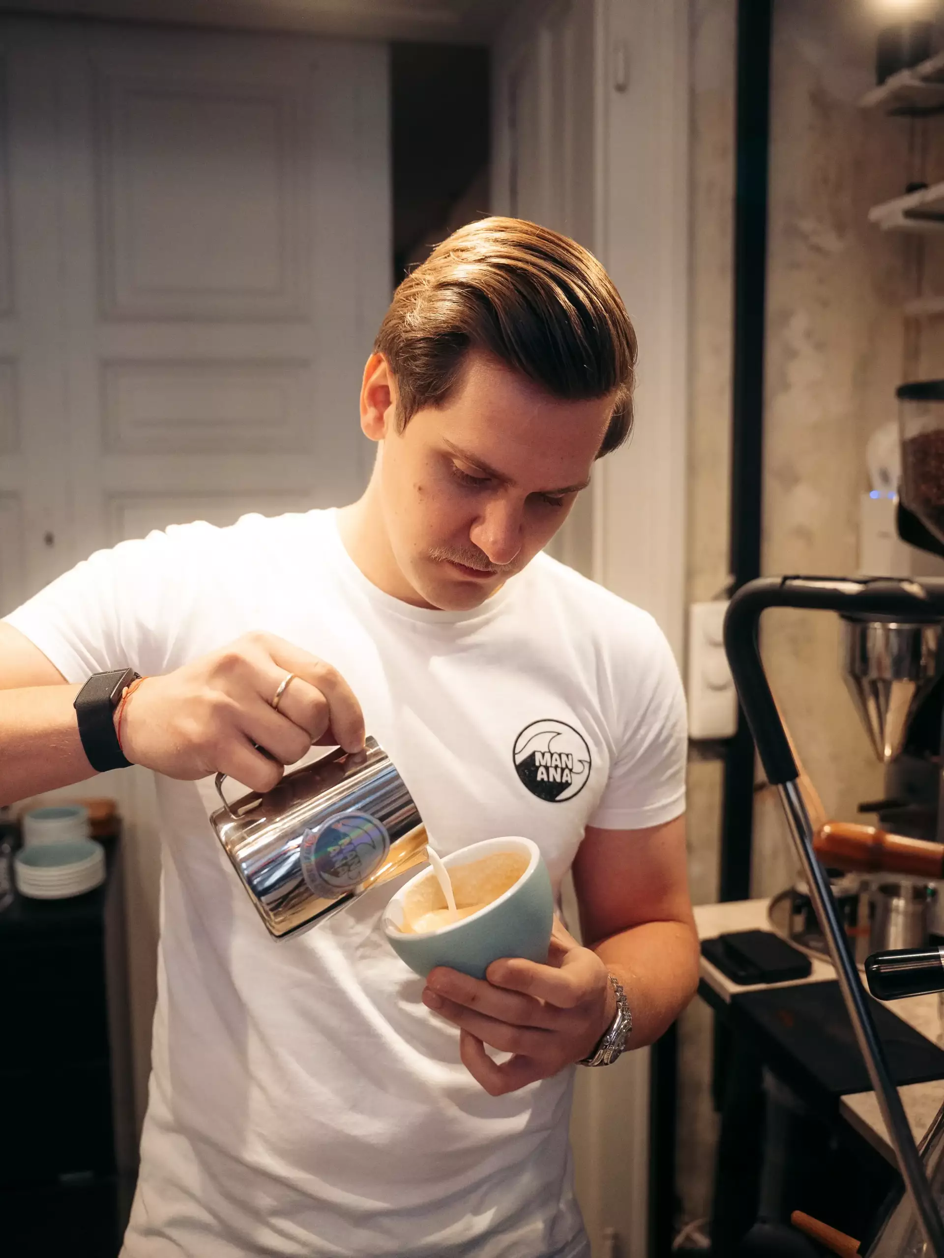 Latte Art Workshop im MANANA cafẽ – Barista gießt Milch für Latte Art in türkise Tasse