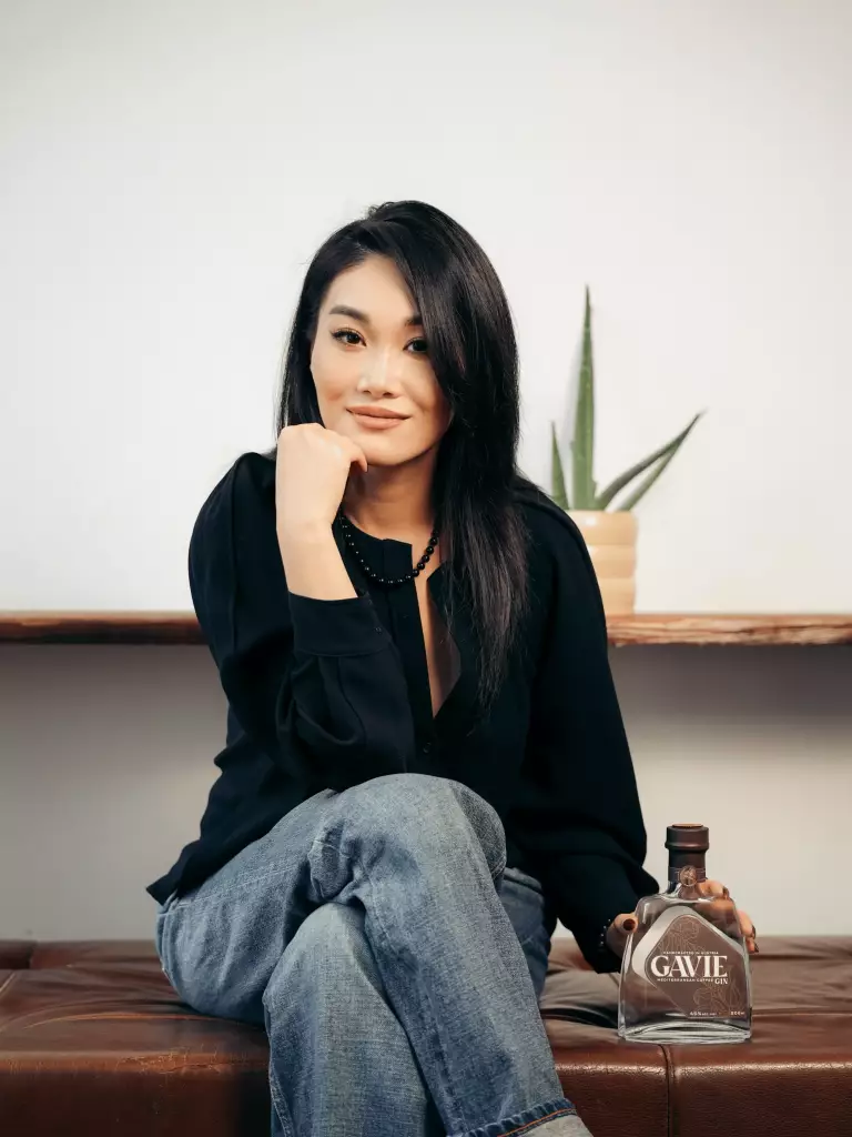 Sherry sitzt im MANANA Café in Wien und hält eine Flasche GAVIE Gin beim DECAF AFTER WORK Event.